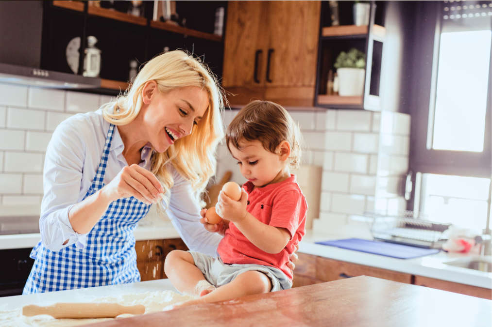 american lady baking in the kitchen with toddler sitting on the kitchen table