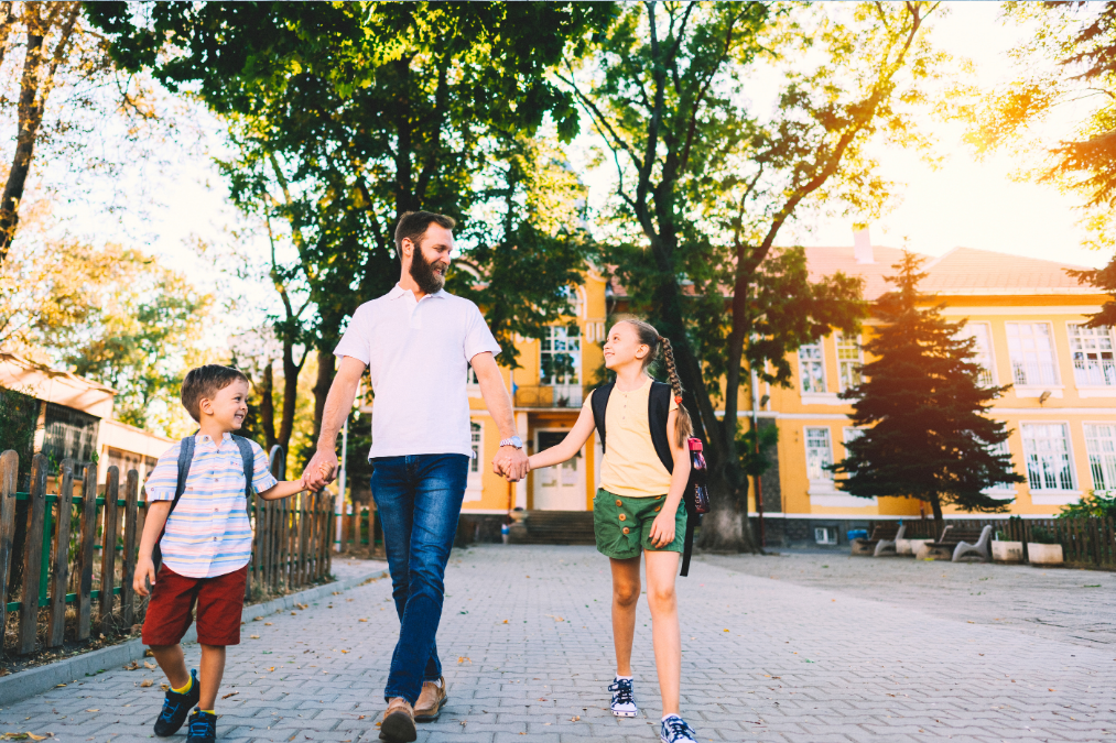 american man walking with his daughter and son to or from school
